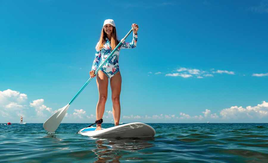 Woman standing on a paddleboard on calm turquoise water near Anna Maria Island